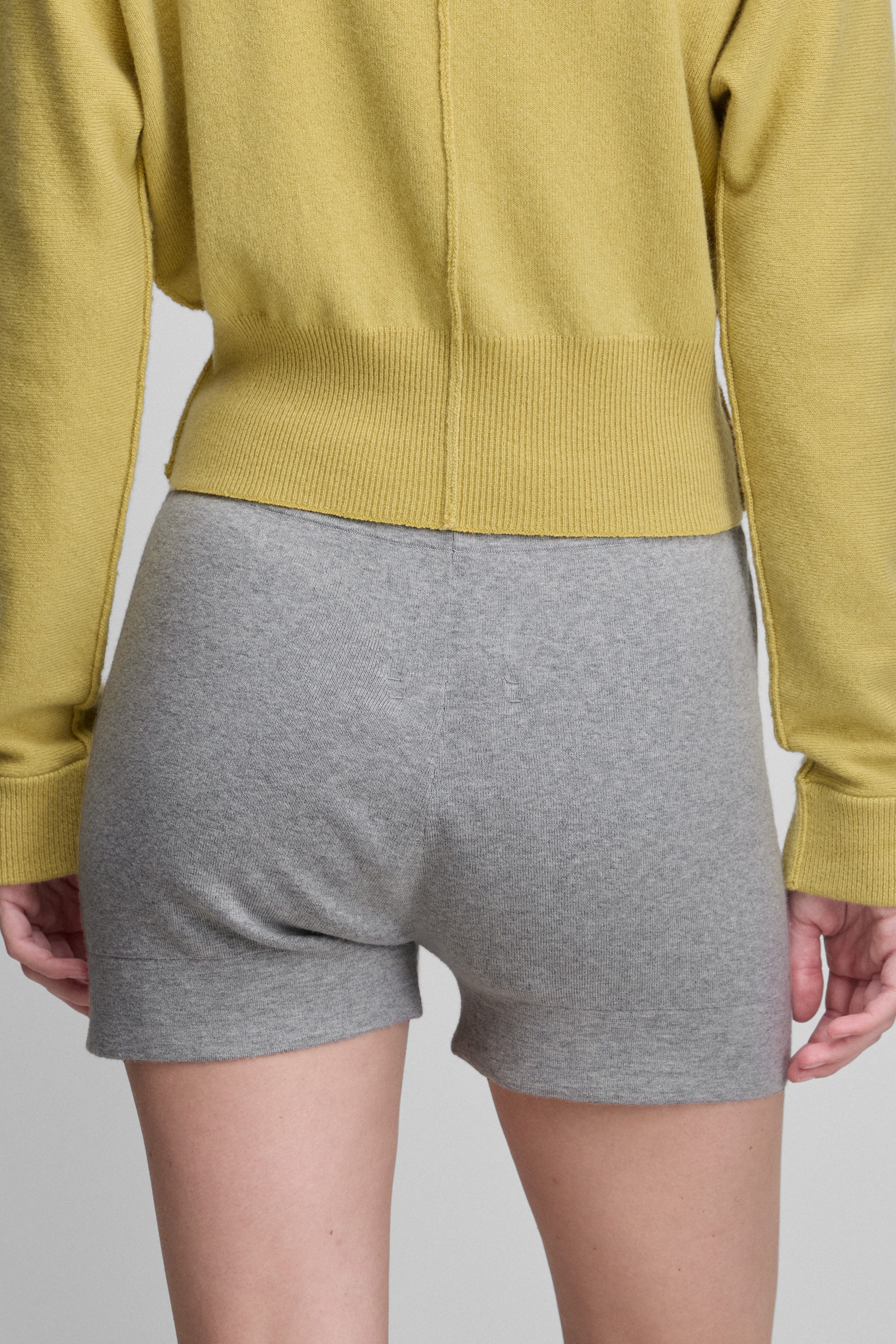 woman wearing fitted grey cotton cashmere rib-knit shorts, shown from the back.