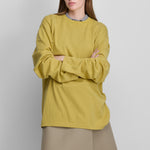 woman wearing a yellow oversized long-sleeved cotton-cashmere t-shirt with a round neckline.