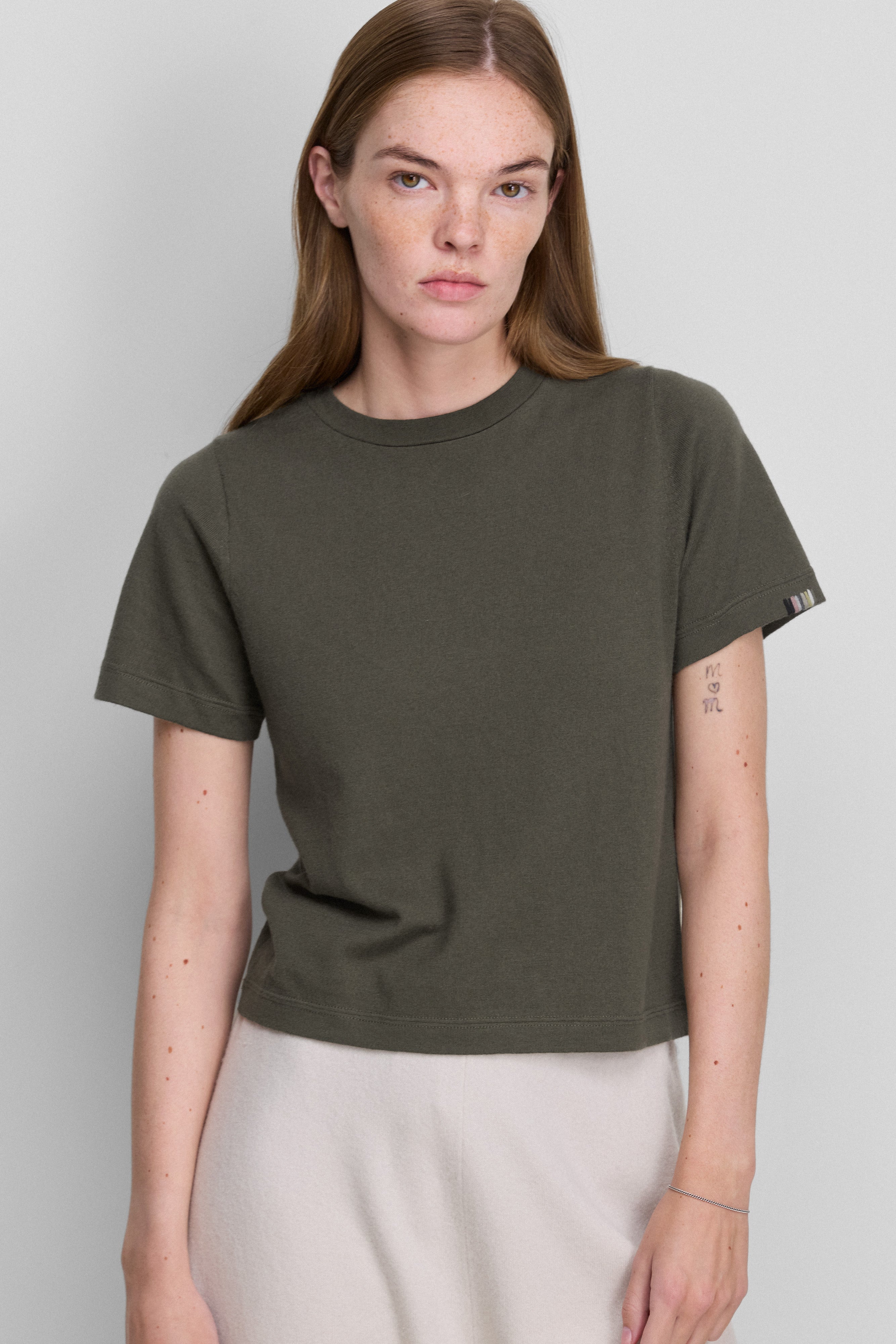 woman wearing an army green cropped short-sleeved cotton cashmere crewneck t-shirt.