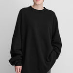 woman wearing an oversized black cashmere crewneck sweater with long sleeves and ribbed trims.
