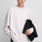 man wearing an oversized white cashmere crewneck sweater with ribbed trims.