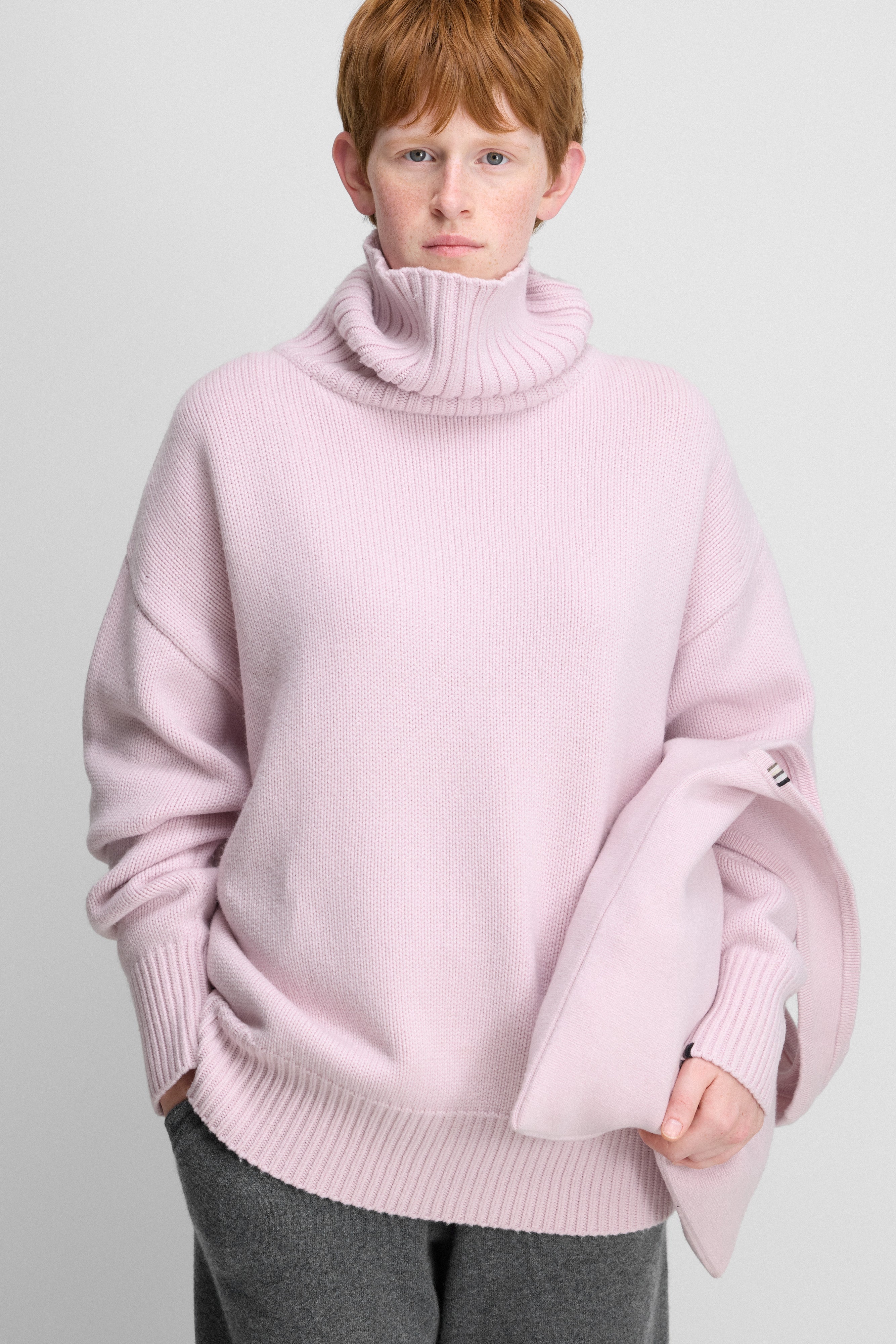 woman wearing a light pink heavy-knit cashmere turtleneck sweater with ribbed trims.